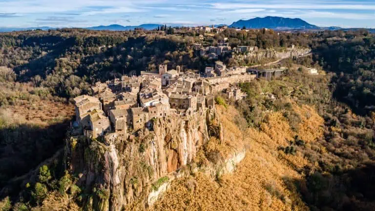 Aerial view of the medieval village of Calcata with its volcanic cliff and the valley of the Treja river with Mount Soratte in the background.
